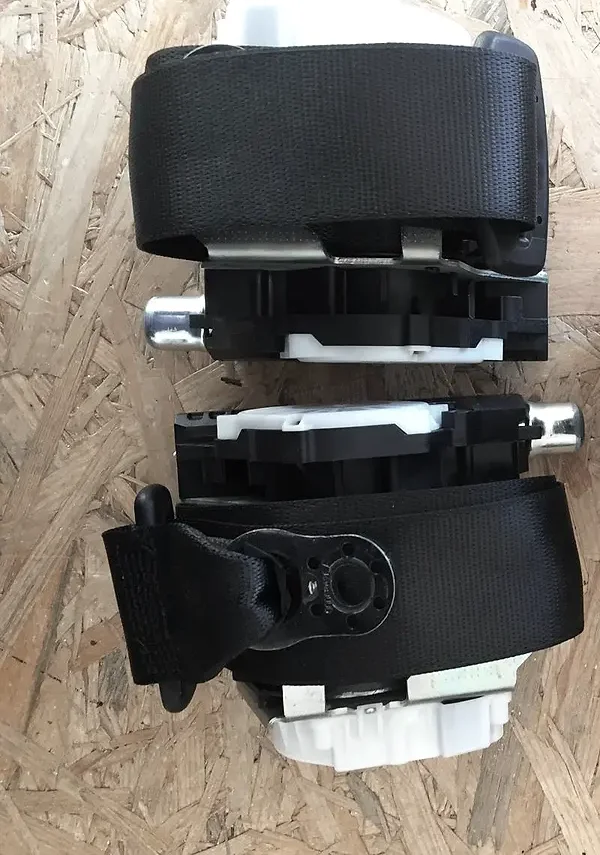 Two seat belt retractors on a wooden workshop floor